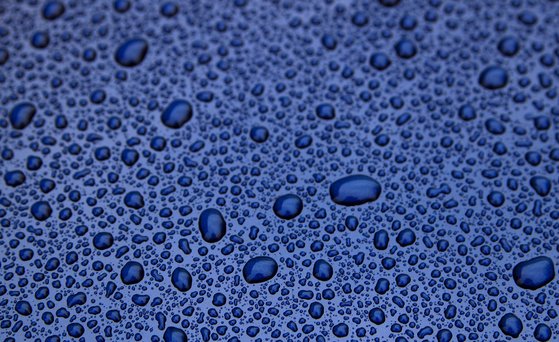 Makroaufnahme, Wassertropfen perlen auf imprägnierter Oberfläche ab.