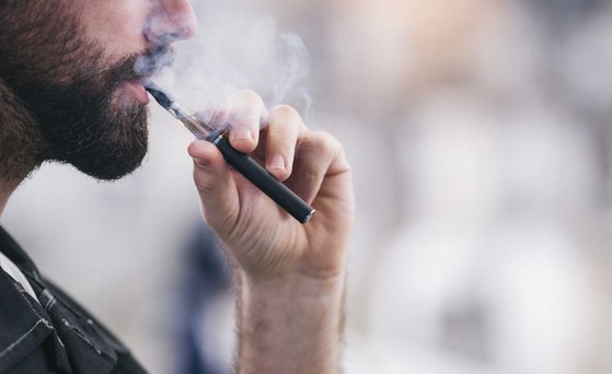 Männliche Person zieht an einer E-Zigarette.