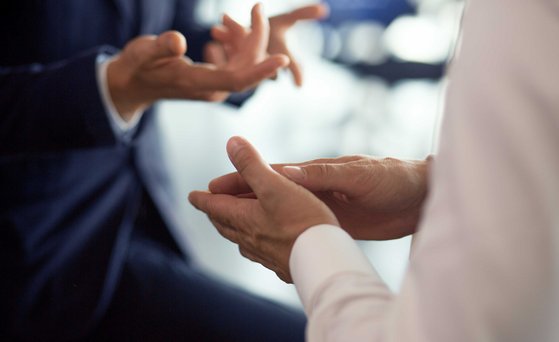 Gestikulierende Hände von zwei Personen, die im Gespräch sind.
