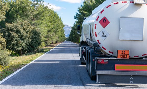 Fahrzeug, LKW, Tankfahrzeug, mit Warnschildern. Von hinten fotografiert, vorbei am Fahrzeug auf linker Spur.