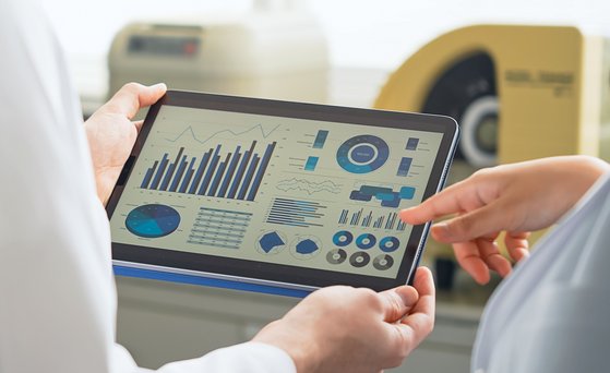 Analytik Tablet mit Diagrammen wird von zwei Personen im weißen Kittel gehalten.