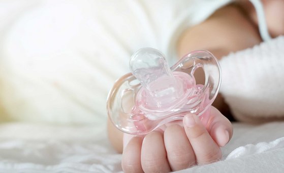 Babyhände halten rosa Schnuller.