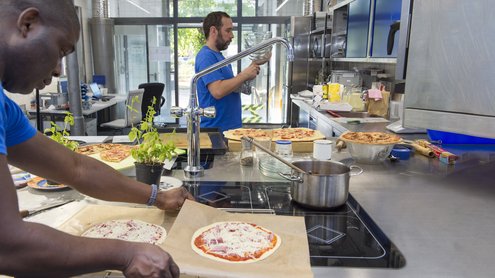 Mann packt Pizza in einer Industrieküche