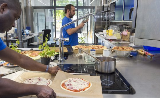 Mann packt Pizza in einer Industrieküche