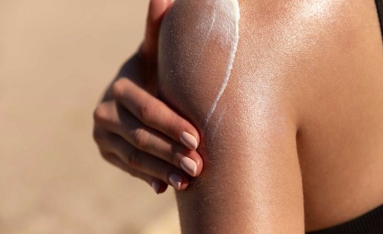 Sonnencreme wird auf Schulter aufgetragen.