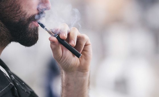 Männliche Person zieht an einer E-Zigarette.