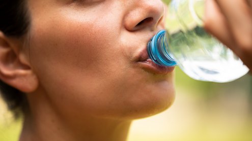 Frau trinkt aus einer Plastikflasche