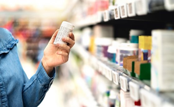 Person standing at the supermarket shelf holding packaging in their hands