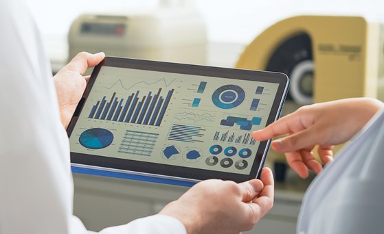 Analytik Tablet mit Diagrammen wird von zwei Personen im weißen Kittel gehalten.