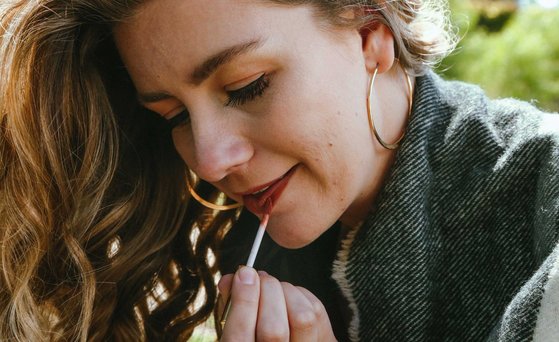 Kosmetische Mittel Woman applies red lipstick